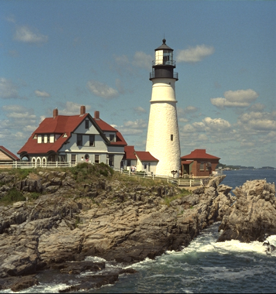 Houses with a lighthouse on top of a cliff above sea, narrower with without cut in the lighthouse.
